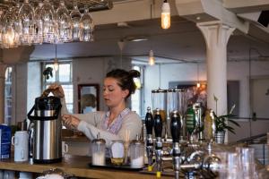 a woman bartender behind a counter at a bar at Sleep in Heaven in Copenhagen