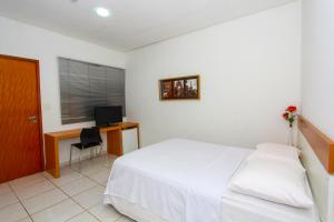 a bedroom with a bed and a desk with a television at Hotel Talissa 2 in Manaus