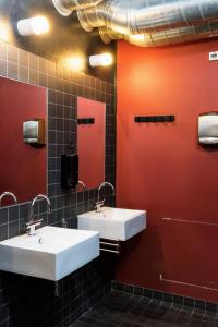 two sinks in a public bathroom with red walls at Sleep in Heaven in Copenhagen