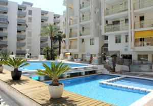 a large swimming pool with palm trees in front of buildings at Novelty I in Salou