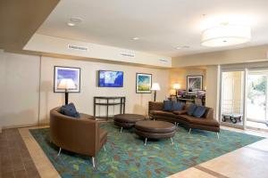 Candlewood Suites - Jacksonville - Mayport, an IHG Hotel في جاكسونفيل: غرفة معيشة بها كنب وكراسي وطاولة