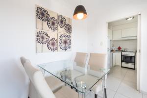 a dining room with a glass table and white chairs at AT Suites in Córdoba
