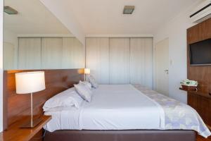 a bedroom with a white bed and a flat screen tv at AT Suites in Córdoba