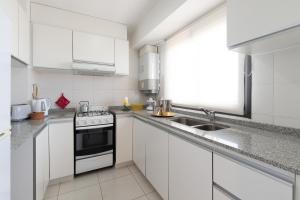 a white kitchen with a sink and a stove at AT Suites in Córdoba