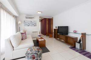 a living room with a white couch and a tv at AT Suites in Córdoba