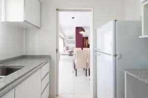 a kitchen with white cabinets and a dining room at AT Suites in Córdoba