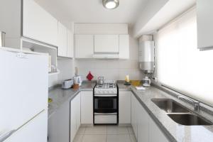 a white kitchen with a stove and a sink at AT Suites in Córdoba