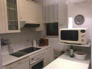 a white kitchen with a microwave and a sink at Panoramic view near the beach in Portotož+P in Portorož +14 photos