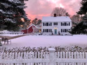 a white house with a fence in the snow at Silvershell Inn in Marion