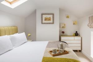 a white bedroom with a bed and a dresser at Harewood Estate Cottages in Harewood