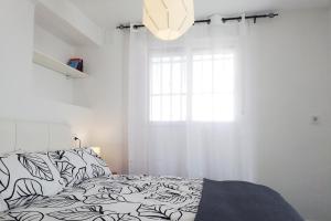 トレ・デル・マールにあるAtico del Marの白いベッドルーム(ベッド1台、窓付)