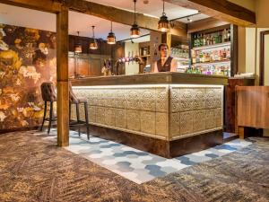 a bar with a woman behind the counter at The Feathers Hotel in Ludlow