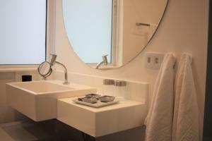 La salle de bains blanche est pourvue d'un lavabo et d'un miroir. dans l'établissement Design e sofisticação em Higienópolis, à São Paulo
