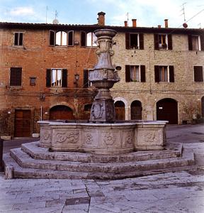 a stone fountain in front of a brick building at La Torre in Asciano