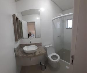 Baño blanco con lavabo y aseo en Apartamento 2 dormitório praia de Bombas, en Bombinhas