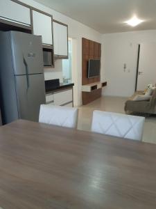 cocina con mesa, sillas y nevera en Apartamento 2 dormitório praia de Bombas, en Bombinhas