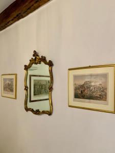 un miroir accroché sur un mur avec des photos. dans l'établissement B&B Fortuny, à Venise