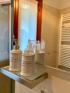 une salle de bains avec trois distributeurs de savon sur une étagère dans l'établissement B&B Fortuny, à Venise