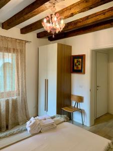 - une chambre avec un lit blanc et un lustre dans l'établissement B&B Fortuny, à Venise