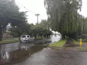 a white car driving down a street in the rain at Hospedaje Bernardita in Valdivia +3 photos