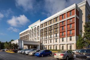 un gran edificio blanco con coches aparcados en un aparcamiento en Holiday Inn Express Atlanta Airport-College Park, an IHG Hotel en Atlanta