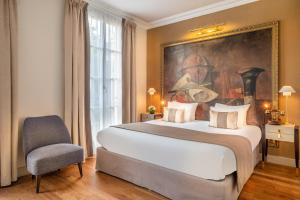 a bedroom with a bed, chair, lamp and a painting on the wall at Hôtel Le Walt in Paris