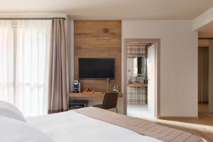 a bedroom with a bed and a desk and a tv at QC room San Pellegrino in San Pellegrino Terme