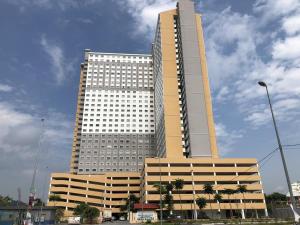 a tall building with palm trees in front of it at ORKED BELLINA, 3 Bedroom apartment, near Pantai Batu Burok, NETFLIXWIFIYOUTUBE in Kuala Terengganu