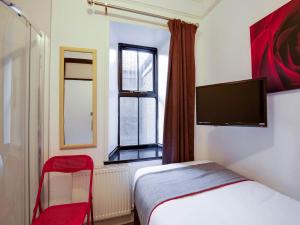 um quarto com uma cama, uma televisão e uma janela em Lost Guest House Peterhead em Peterhead