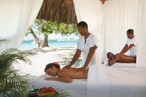 
a man and woman sitting on top of a bed at Couples Negril in Negril
