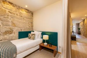 a bedroom with a bed and a stone wall at YOUROPO - Ribeira Gaia in Vila Nova de Gaia