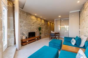 a living room with a blue couch and a stone wall at YOUROPO - Ribeira Gaia in Vila Nova de Gaia