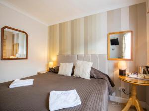 a bedroom with a bed and a table with a mirror at OYO Arden Guest House, Craigmillar Castle Edinburgh in Edinburgh