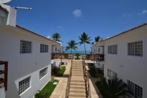 uma passagem entre dois edifícios com o oceano ao fundo em Itamaracá Apartments em Itamaracá