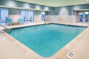 a pool in a hotel room with blue chairs at Holiday Inn Express & Suites Kingdom City by IHG in Kingdom City