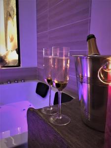 dois copos de vinho sentados numa mesa ao lado de uma banheira em GOLD Suite & Spa em Nantes