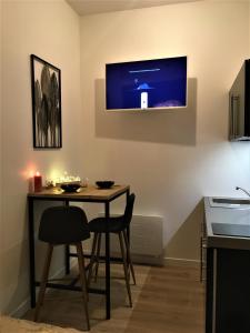 a kitchen with a table and a tv on the wall at GOLD Suite & Spa in Nantes