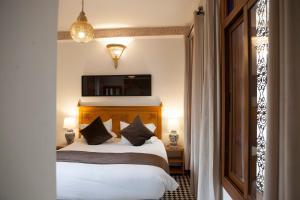 a bedroom with a bed with white sheets and pillows at Dar D'or Fes in Fès