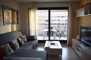 a living room with a couch and a tv and a balcony at Apartacona-Playa in Valencia