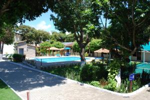 einen Pool in einem Resort mit Bäumen und einem Gebäude in der Unterkunft Hotel Rusticos in Conceição da Barra