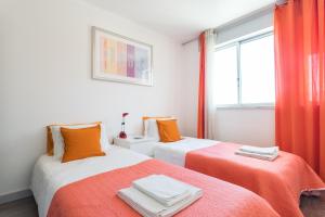 dwa łóżka w pokoju pomarańczowo-białym w obiekcie Parque das Nações, near Airport, Metro Station w Lizbonie
