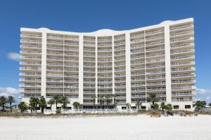 um grande edifício branco na praia com palmeiras em Admirals Quarters em Orange Beach