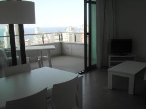 Una sala de estar con una mesa y un balcón con televisión. en Apartamentos con terraza Torre D'Oboe by Renthas, en Benidorm