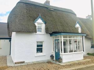 a white house with a thatched roof at Bluebell Cottage in Kilmore Quay