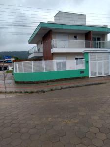 un edificio verde y blanco con aparcamiento en Sua casa fora de casa, en Bombinhas