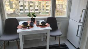 einen weißen Tisch mit zwei Tassen, zwei Stühlen und einem Fenster in der Unterkunft Hamina Orange Apartments Kadetti 2 in Hamina
