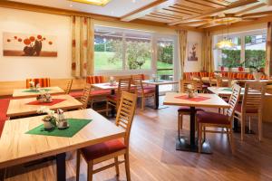a restaurant with wooden tables and chairs and windows at Gästehaus Steger in Kaprun