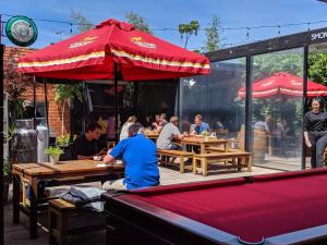 a man sitting at a table under a red umbrella at Royal Derby Hotel in Melbourne