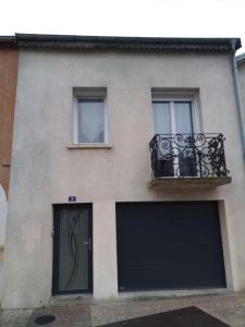 un bâtiment avec deux portes de garage et un balcon dans l'établissement Maison, à Damblain