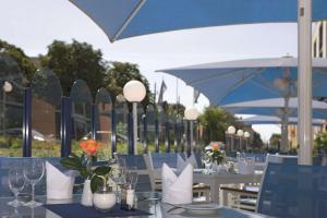 a dining room table with chairs and umbrellas at Radisson Blu Fürst Leopold Hotel in Dessau